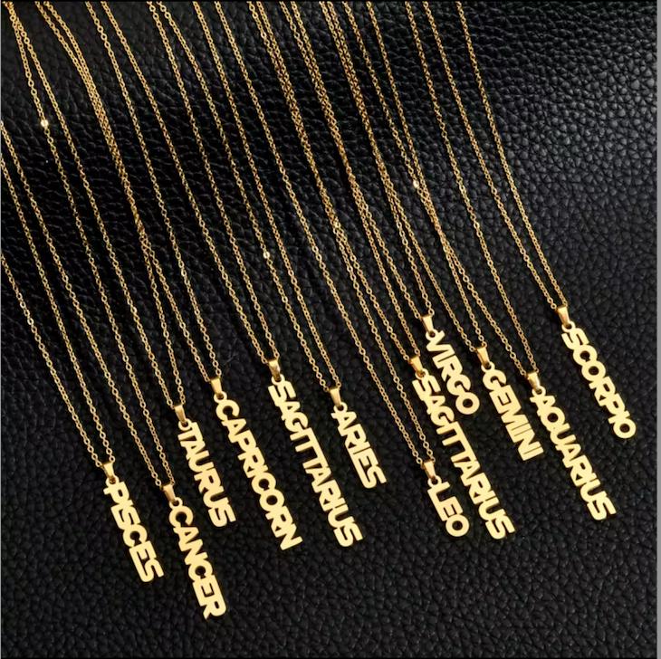 Goldene Halsketten mit vertikalem Sternzeichen-Schriftzug auf schwarzem Hintergrund, sortiert von Pisces bis Scorpio