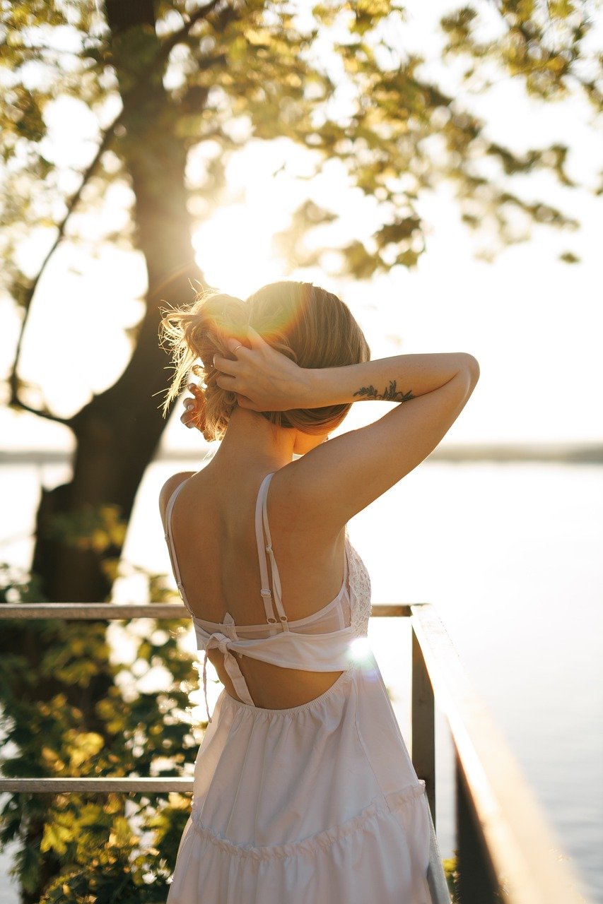 Frau bindet stilvoll ihr Haar zum Dutt – mit Haarschmuck von TREND Kollektiv bei Sonnenuntergang am See“