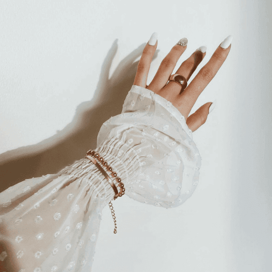 Kollektionsbild Schmuck_zwei Hände in einander verschlungen die Armbänder und Ringe Tragen vor einem rose Farbenen Hintergrund_TREND Kollektiv