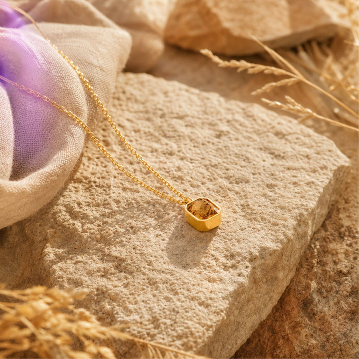 Goldene AMBER LIGHT Kette mit Champagner-Zirkonia auf warmen Naturmaterialien – AI-GENERATED
