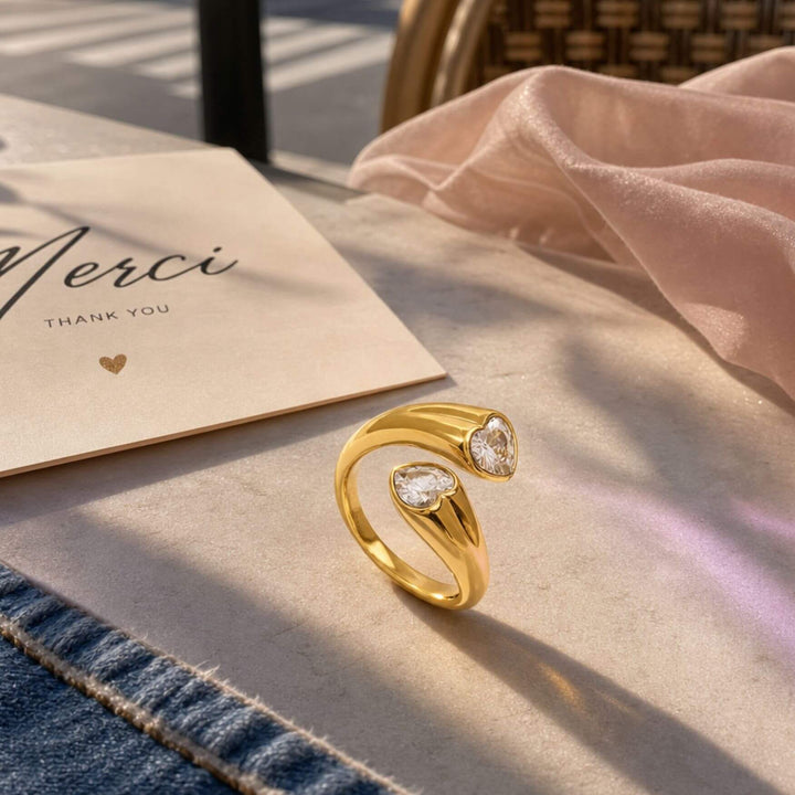 Duo Hearted Ring in Gold auf einem Tsch insziniert als Moodbild in Gold an der Hand eines Models – AI-GENERATED