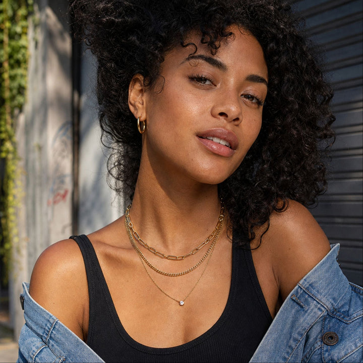 LIV Layer Kette ist eine dreireihige Kette in Gold mit Paperclip-Kette und funkelndem Schmuckstein am Model