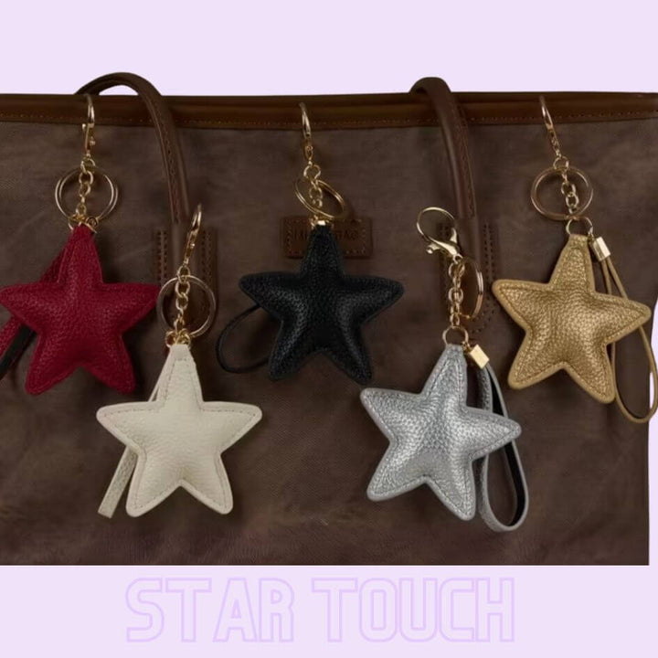 STAR TOUCH Taschenanhänger Sterne in Rot, Beige, Schwarz, Silber und Gold an einer Handtasche – TREND Kollektiv