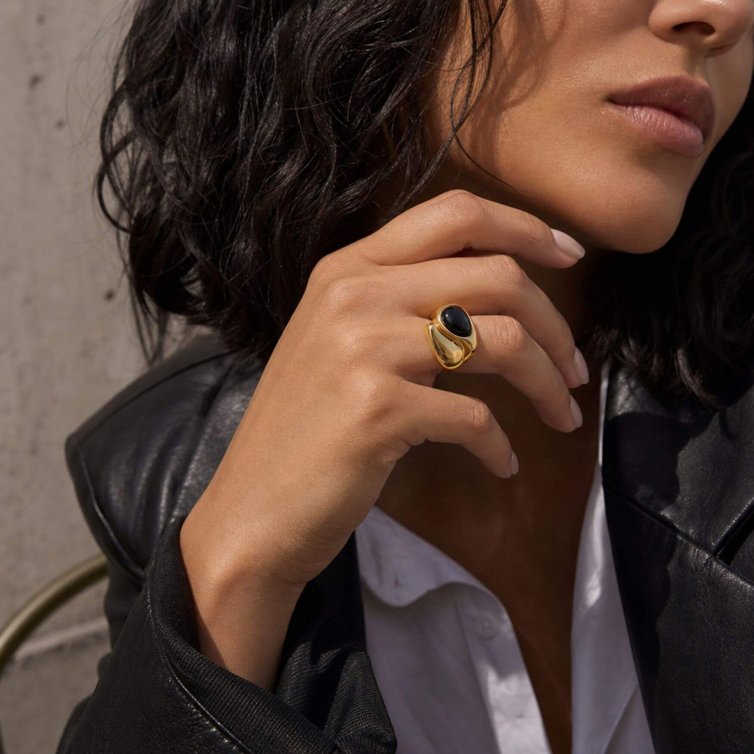 Frau trägt den AURA STONE Ring in Black mit goldfarbenem offenem Design – AI-GENERATED