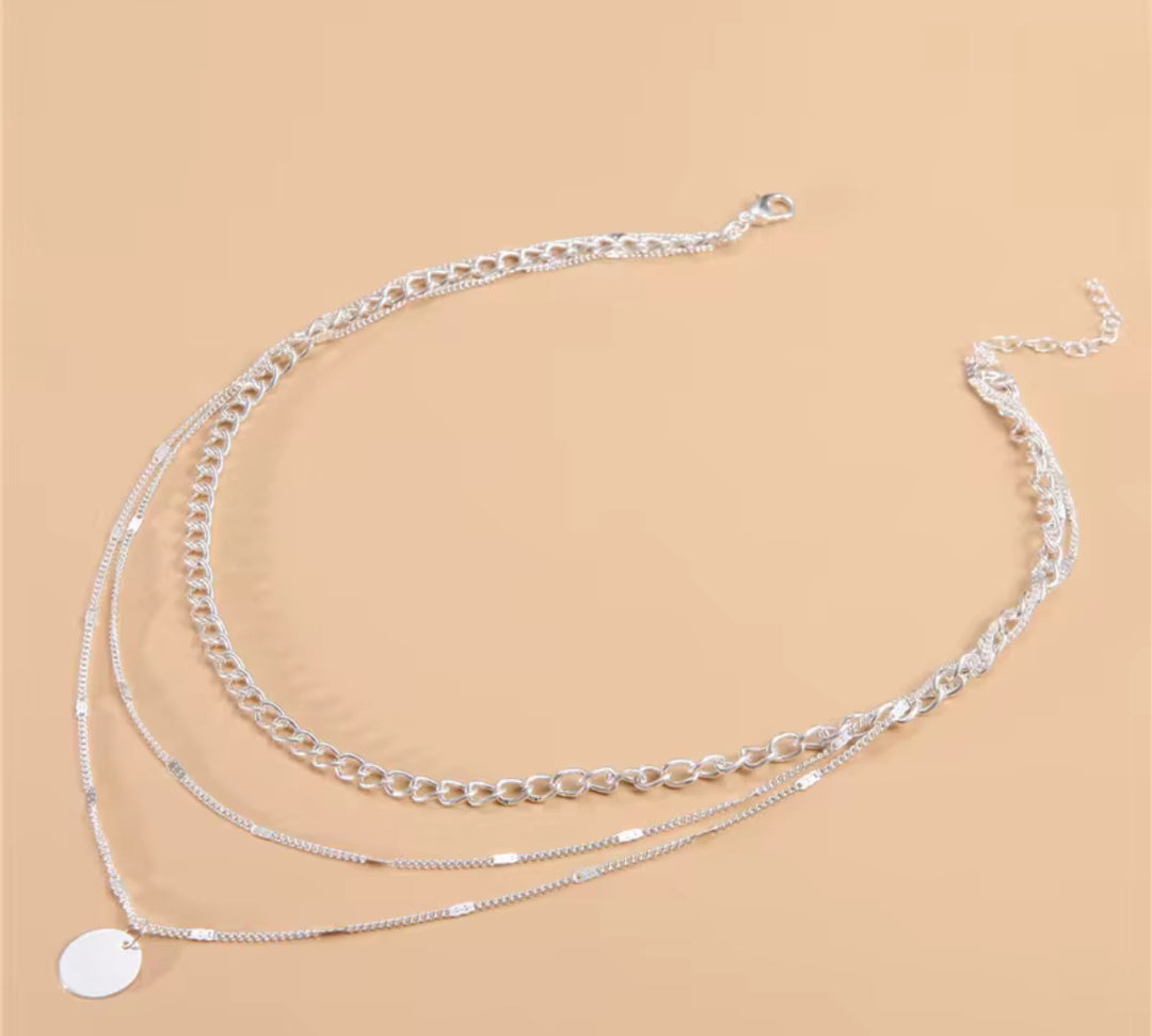 Dreifach-Layerkette in Silber mit schlichter Gliederkette, zarter Plättchenkette und rundem Anhänger – stilvoll und vielseitig.