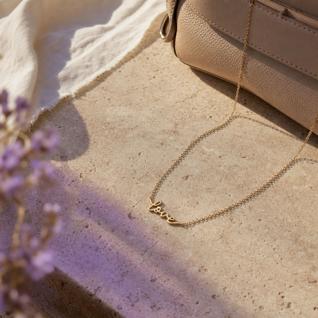 Goldene LOVE Script Kette mit Schriftzug in einem warmen Lifestyle-Setting