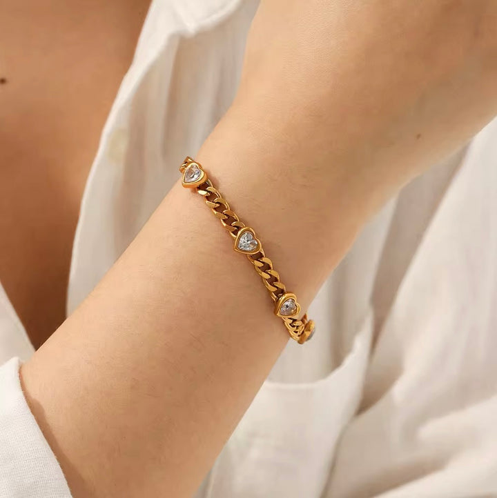 Goldenes Armband mit mehreren Zirkonia-Herzen am Handgelenk einer Frau– TREND Kollektiv