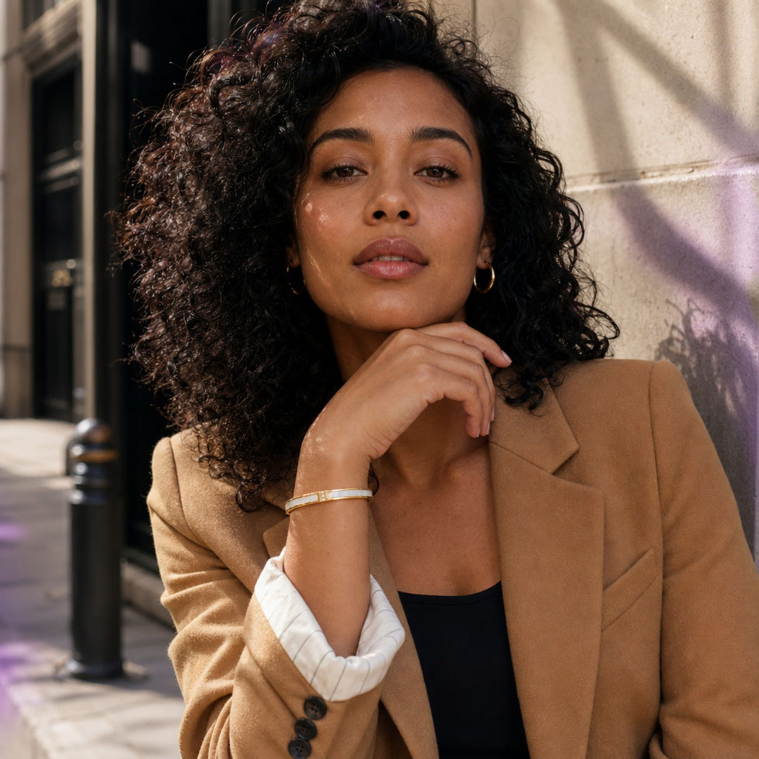 Goldener LUMIÈRE Bangle mit weißer Perlmutt-Optik am Handgelenk eines Models