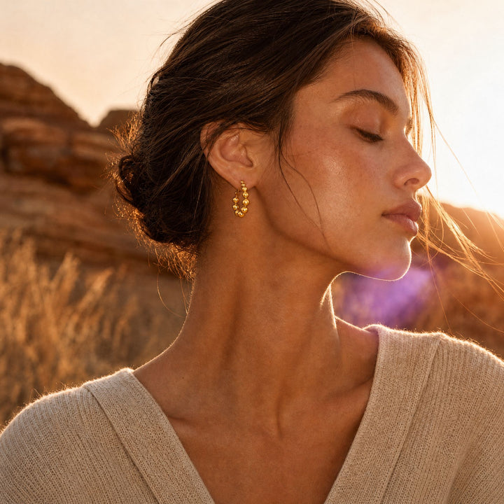 Frau trägt die goldenen ORBIT Bead Hoops im modernen Earth Edit Look – AI-GENERATED
