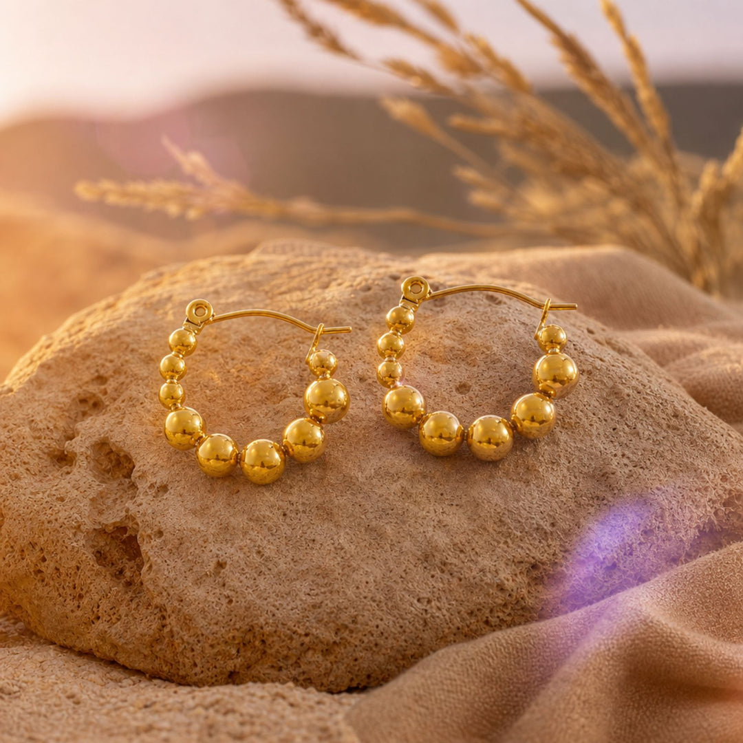 Goldene ORBIT Bead Hoops auf warmen Naturmaterialien – AI-GENERATED
