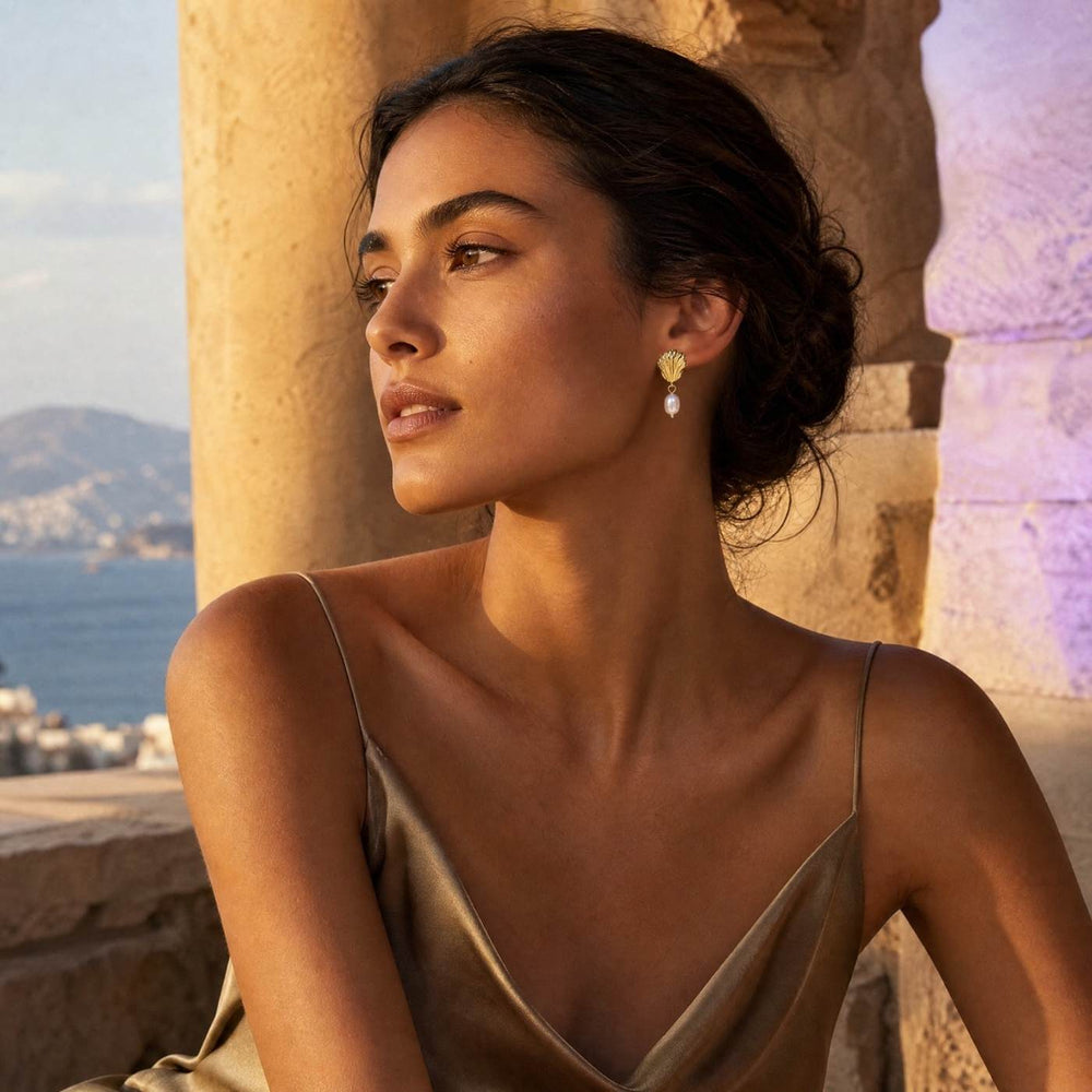 Model trägt die vergoldeten PEARL SHELL Ohrringe mit eleganten Perlendetails im mediterranen Coastal Look – AI-GENERATED