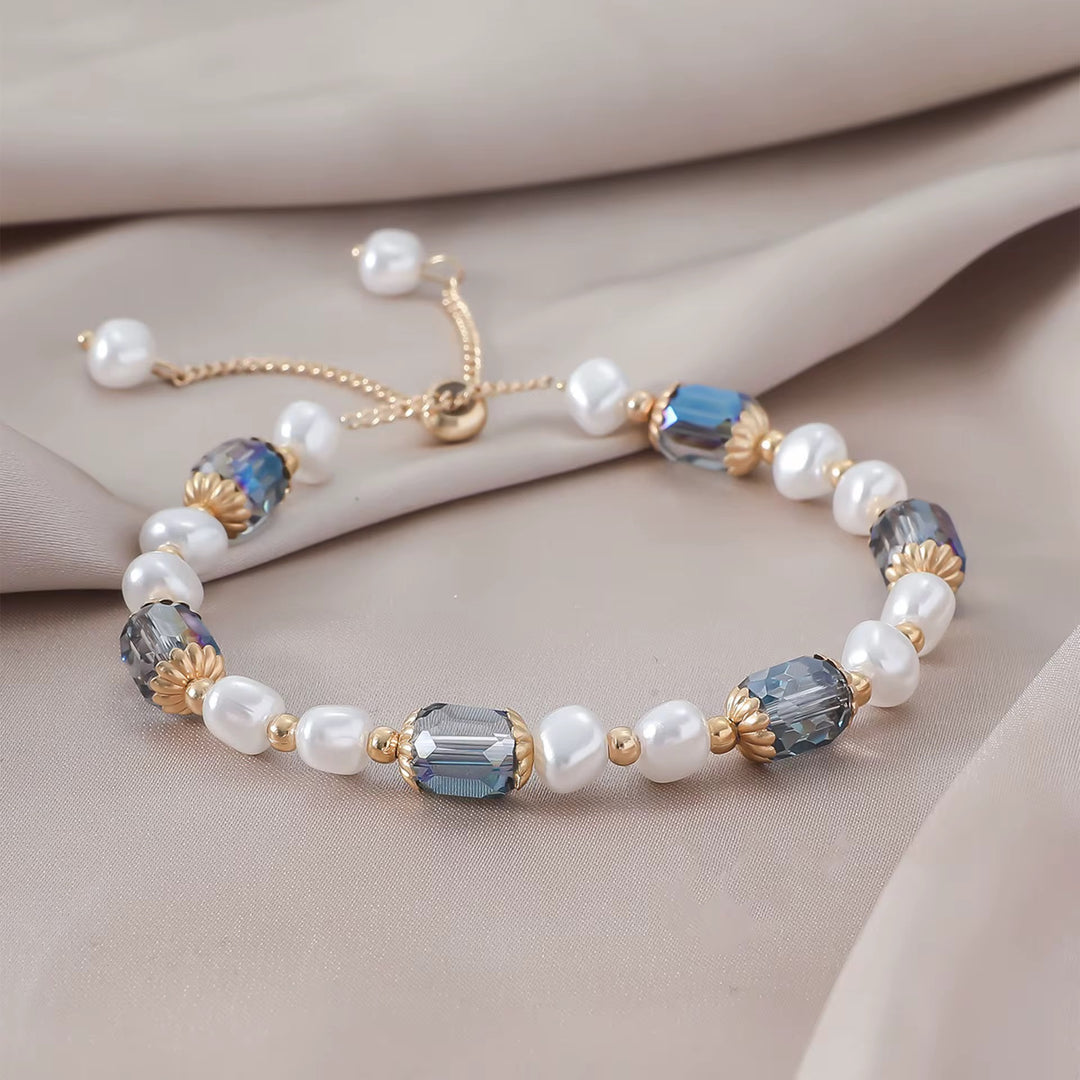 Luxuriöses Armband mit blauen Kristallen, goldenen Akzenten und weißen Zierperlen.