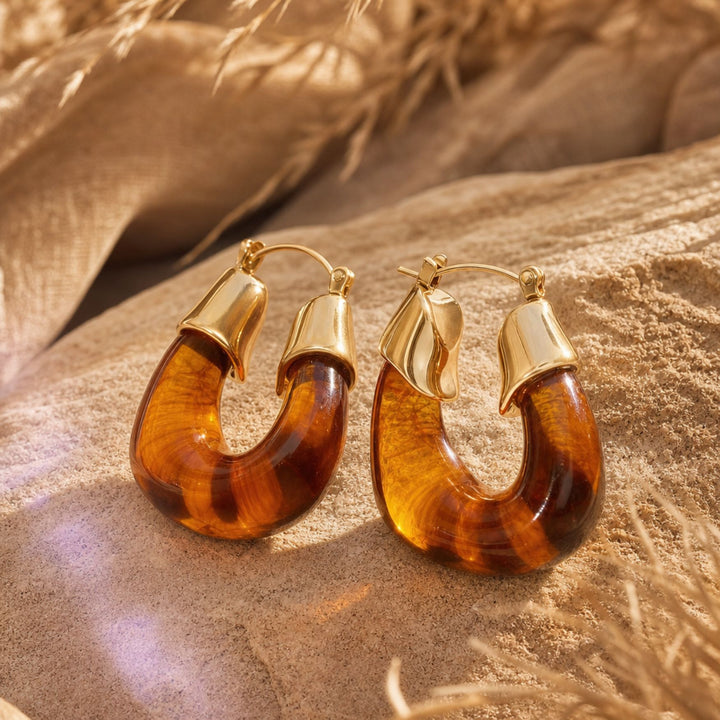 TERRA LOOP Hoops in Amber auf warmen Naturmaterialien – AI-GENERATED