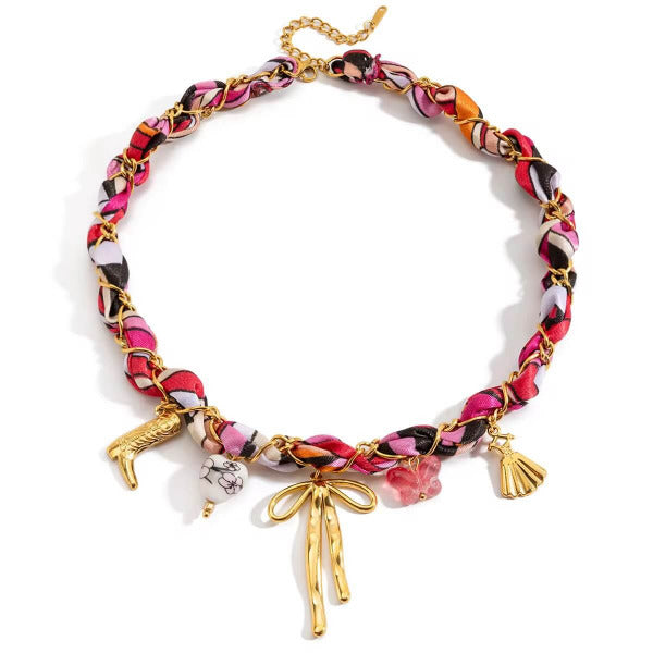 BOW STORY 18k Charmkette mit verflochtenem Textilband, Schleifenanhänger, Herz-, Stiefel- und Schmetterlings-Charms auf weißem Hintergrund – TREND Kollektiv