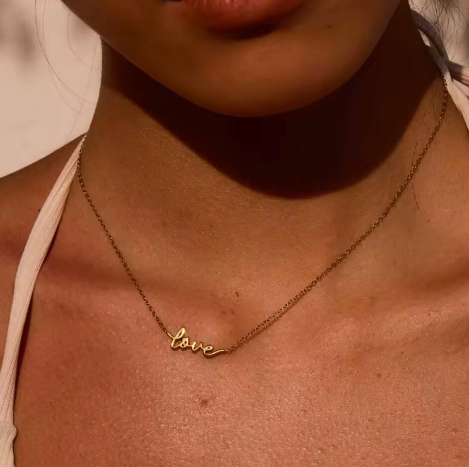 LOVE Script Kette in Goldoptik mit Love-Schriftzug am Hals einer Frau– TREND Kollektiv
